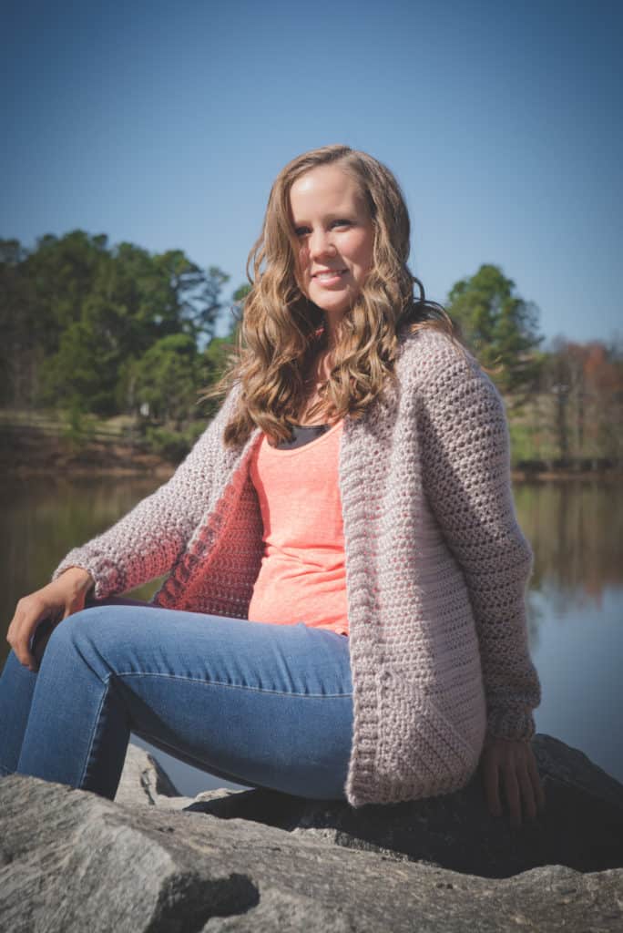 Woman wearing a chunky crochet cardigan, called the Charlotte Cardigan. 