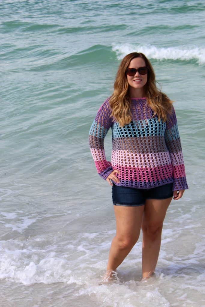 Woman wearing a crochet sweater as a swimsuit cover at the beach. 