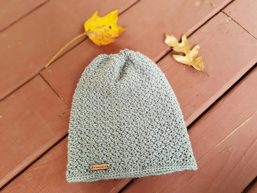 Flat lay photo of a gray crochet slouch hat, called the Boston Slouch. 