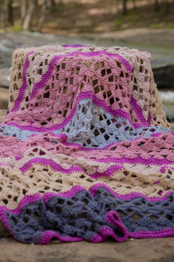 Close up of the Serenity Blanket. Colors used are dark grey, light grey, rose pink, dark pink, and cream.