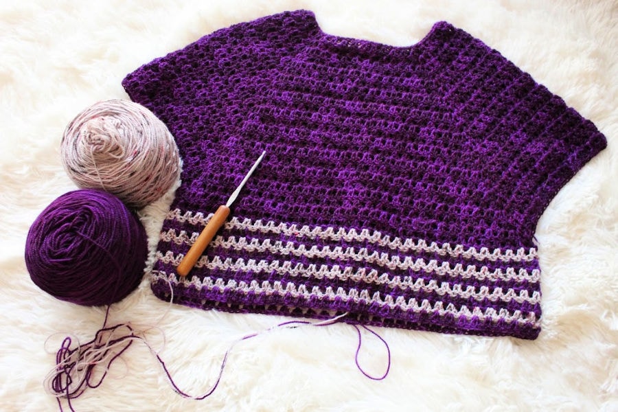 A flatlay of the Leilani Raglan Tee crochet top with a crochet hook and yarn beside it. 