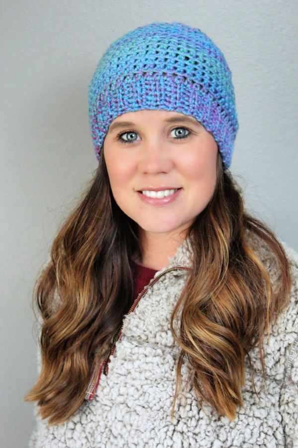 Woman wearing a blue and pink crocheted hat called the KJ Hat. 