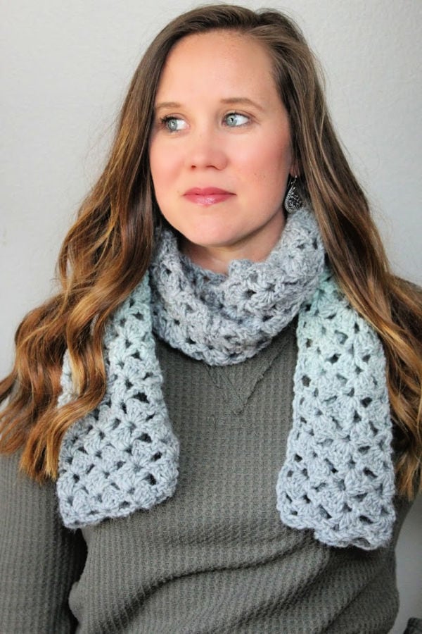 Woman wearing green and gray delightful scarf around her neck.