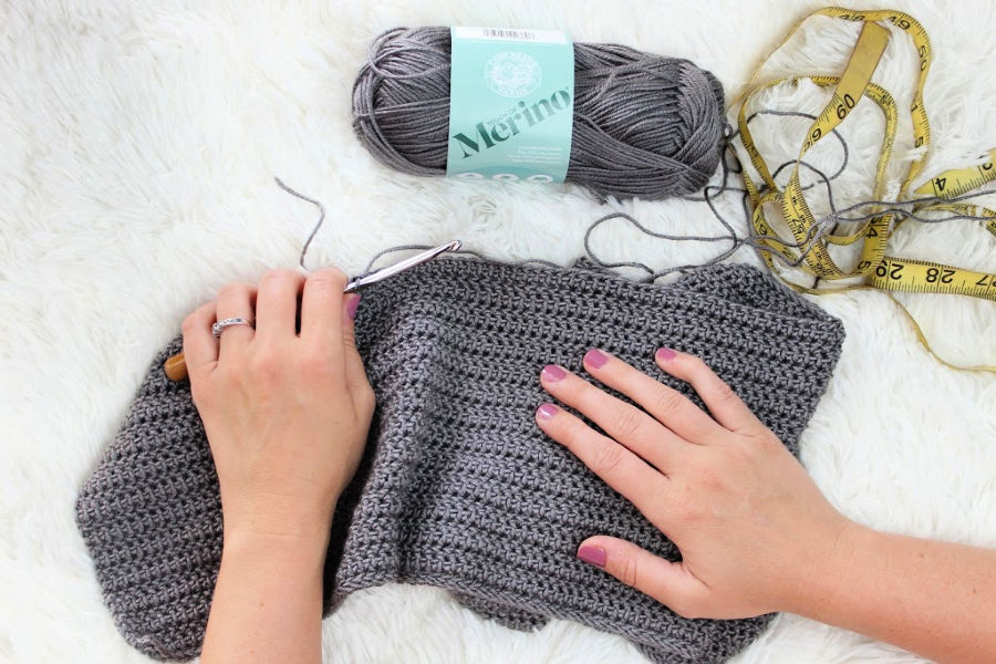 A woman crocheting with gray yarn. 