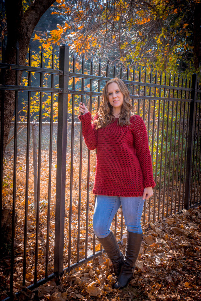 Woman wearing a crochet sweater in dark red, called the Raleigh Tunic. 