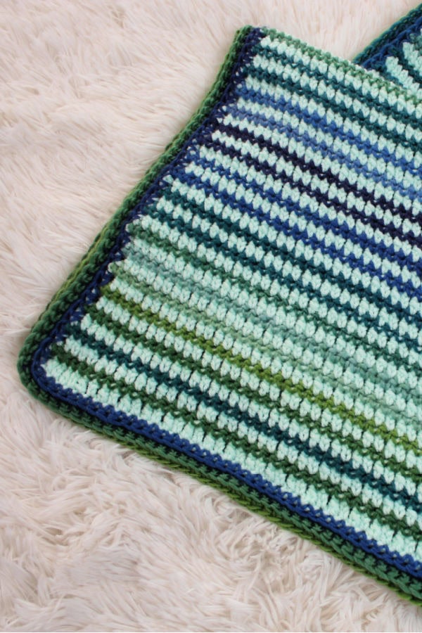 Close up of the preemie crochet blanket, called the Friendship Blanket. The blanket is mint green with blue and green stripes. 