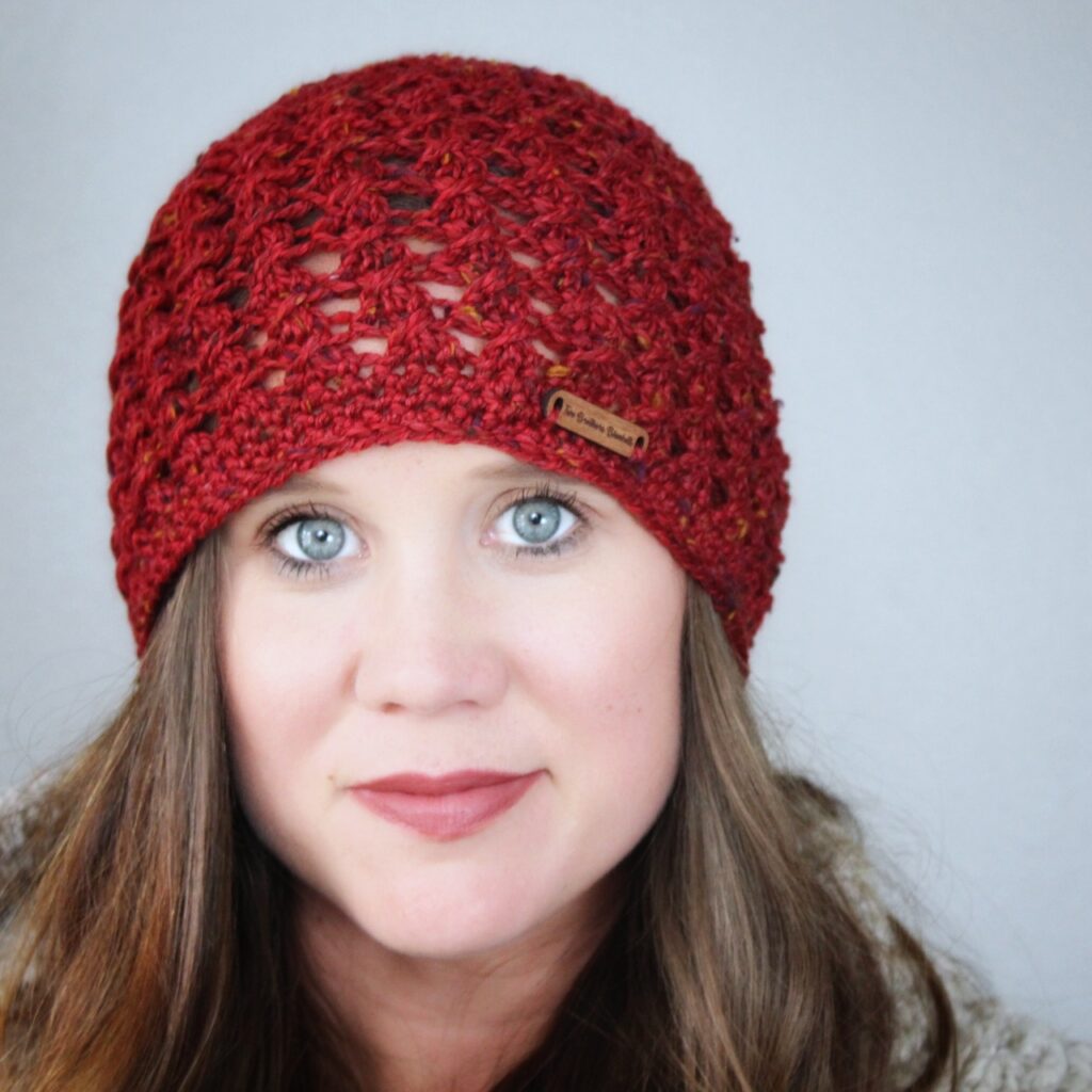 Close up of woman wearing a red crochet beanie, called the Bonnie Bell Beanie. 