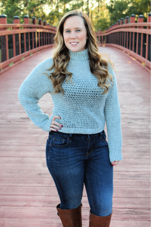Woman wearing a gray sweater, that is a great beginner crochet sweater and called the Bombshell Sweater. 