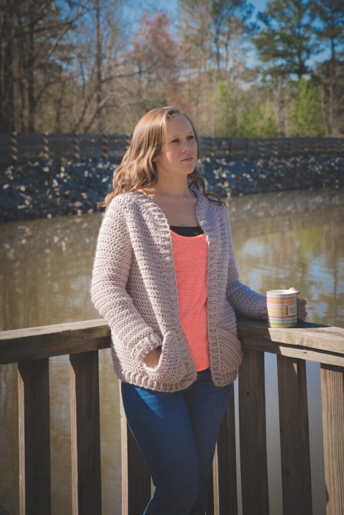 Woman wearing a chunky crochet cardigan, called the Charlotte Cardigan. 