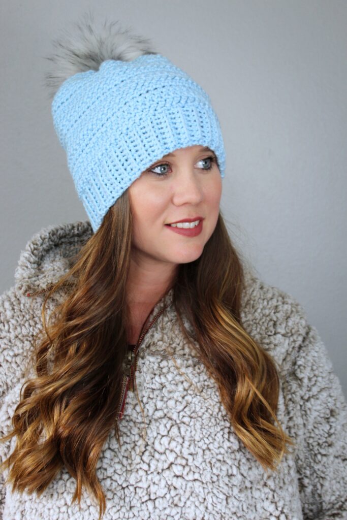 Woman wearing a light blue crochet hat called the Hope Hat. 