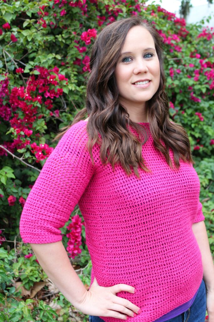 Woman wearing a pink crochet sweater, called the Springtime Sweater.