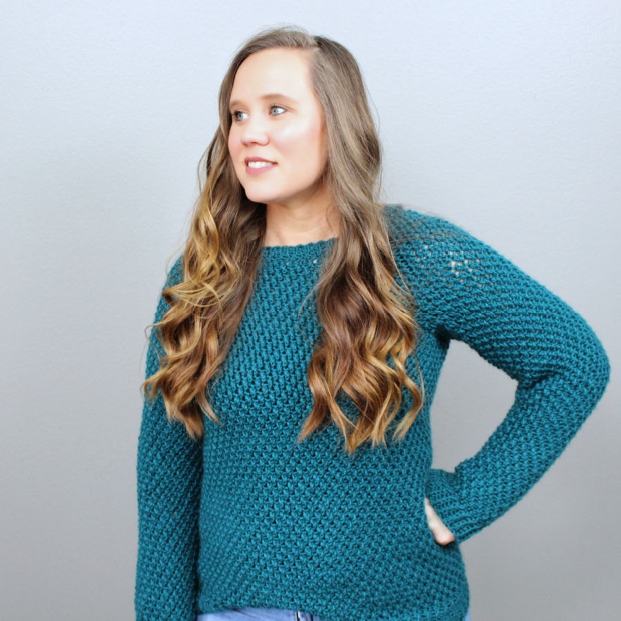 Woman wearing a green crochet sweater, called the Savannah Sweater. 