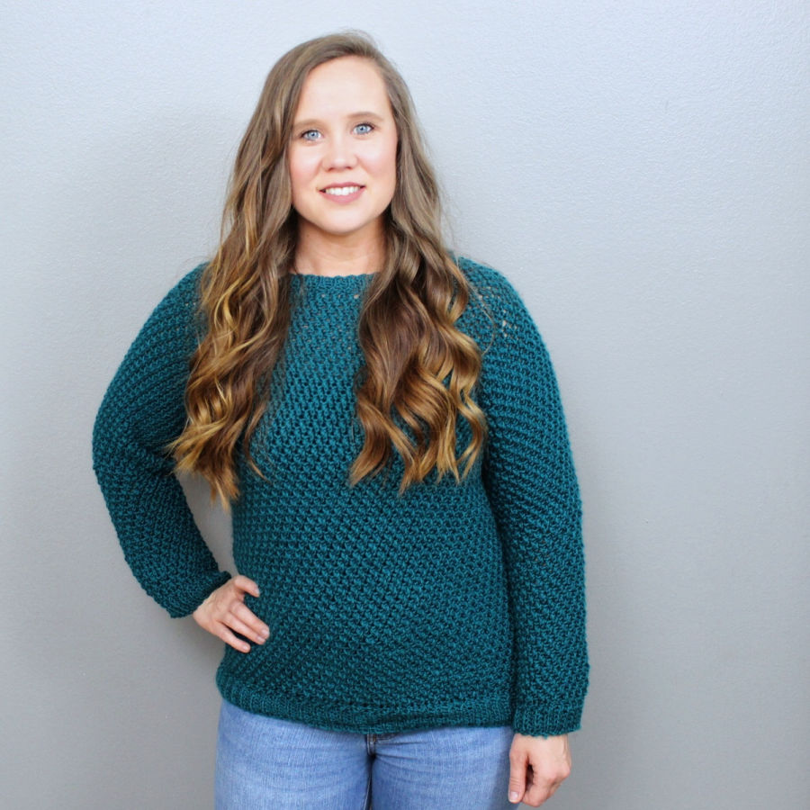 Woman wearing a green crochet sweater, called the Savannah Sweater. 