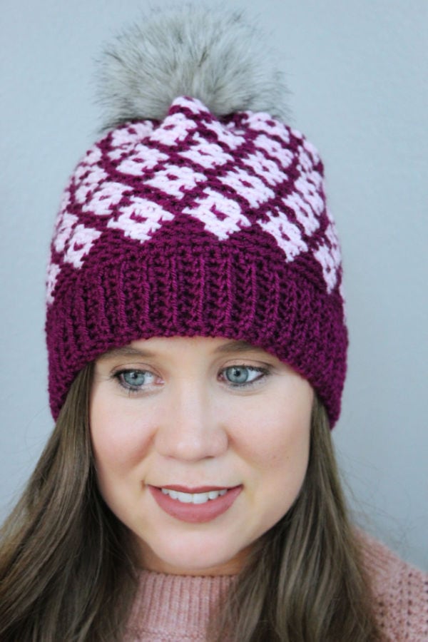 Close up of woman wearing a pink fair isle crochet hat, called the Illusion Hat. 