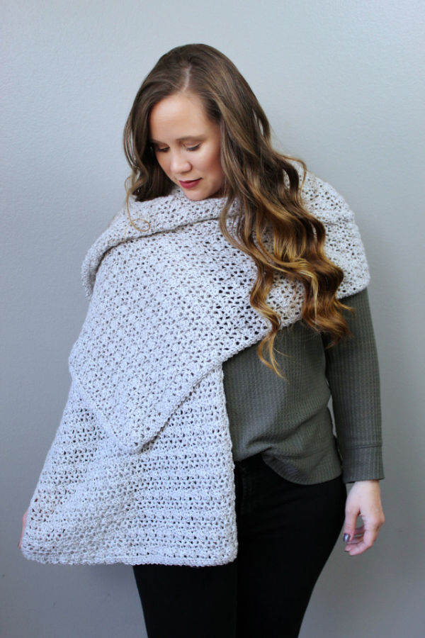 Woman wearing a long light gray crochet wrap, called the Katie Wrap. 