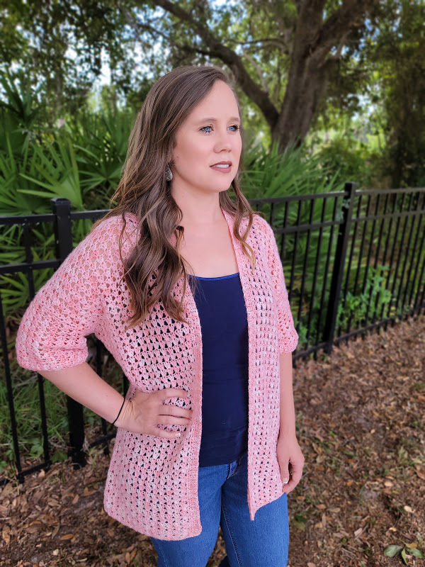 Woman wearing a light pink oversized summer crochet cardigan, called the Jayda Cardigan.