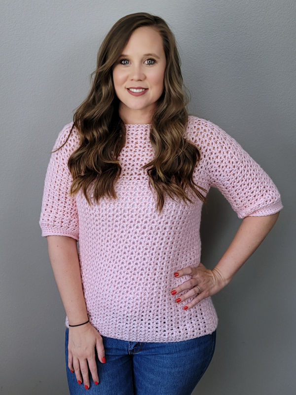 Woman wearing a pink crochet sweater called the Spring Breeze Sweater blouse. 