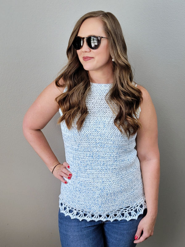 Woman wearing a light blue crochet tank top, called the Beach Bound Tank. 