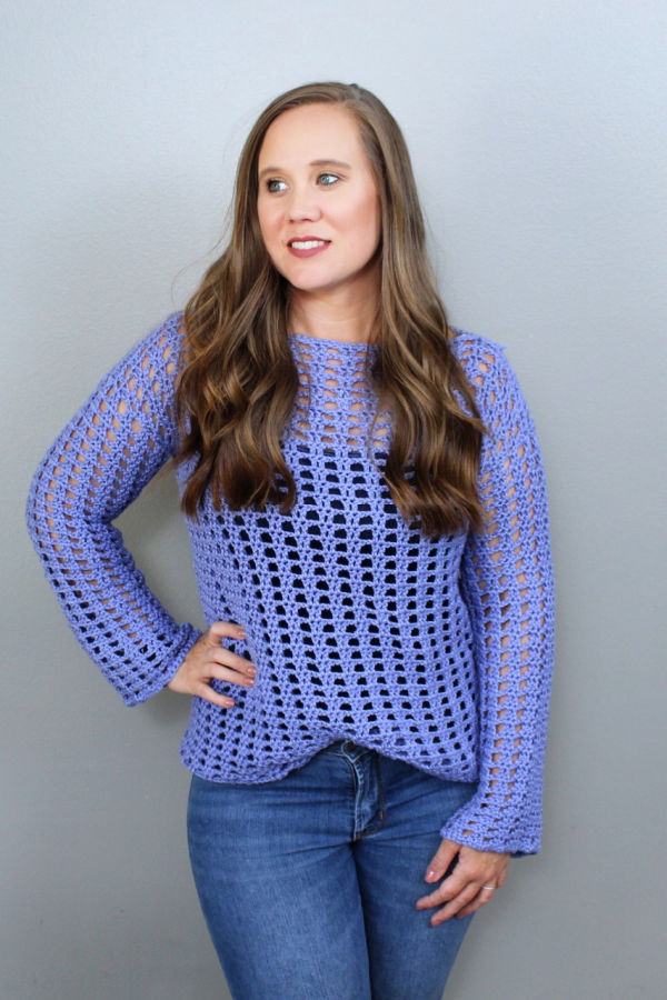 Woman wearing a purple crochet sweater, called the Sassy Summer Sweater.