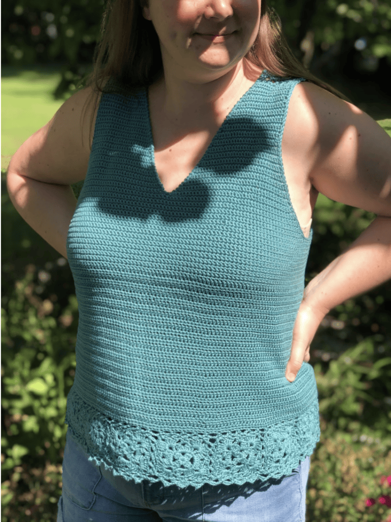 Woman wearing a green crochet tank top, called the Tide Pool Tank. 