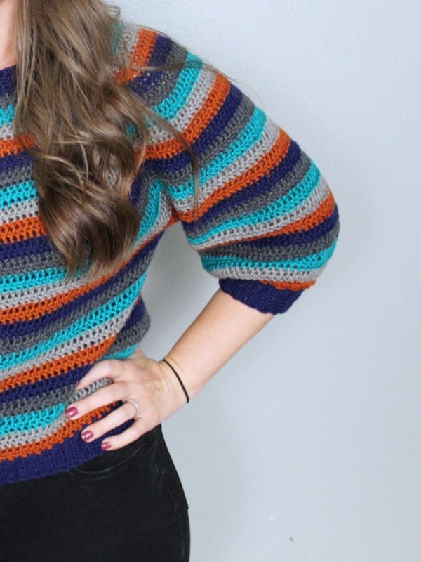 Close up of the sleeve of the Vinnie Sweater, a vintage striped crochet pattern. 