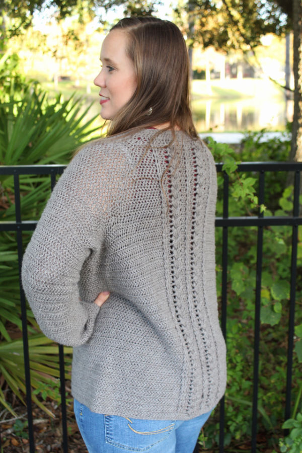Woman wearing a crochet cardigan with cables down the back. 