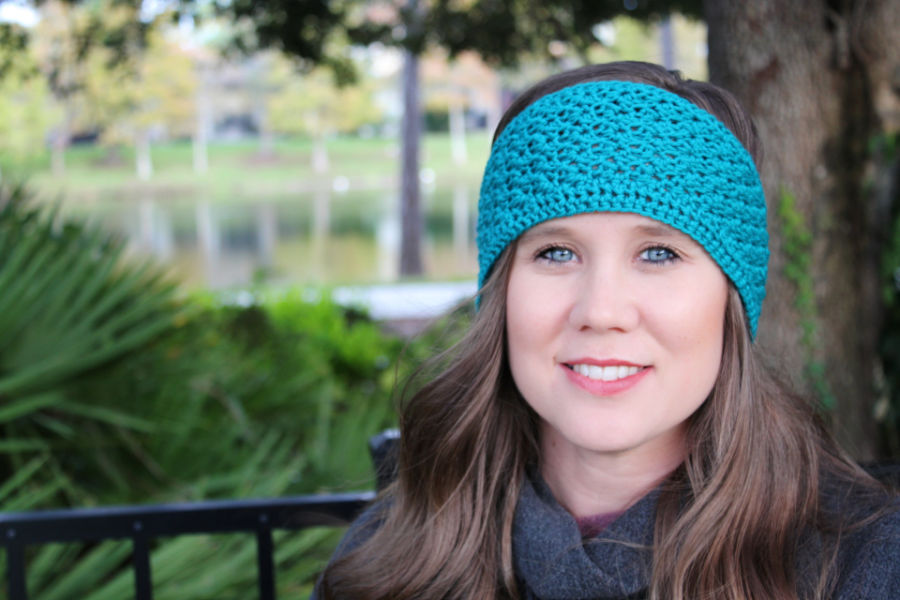 Woman wearing a teal crochet earwarmer, called the Boston Earwarmer. 