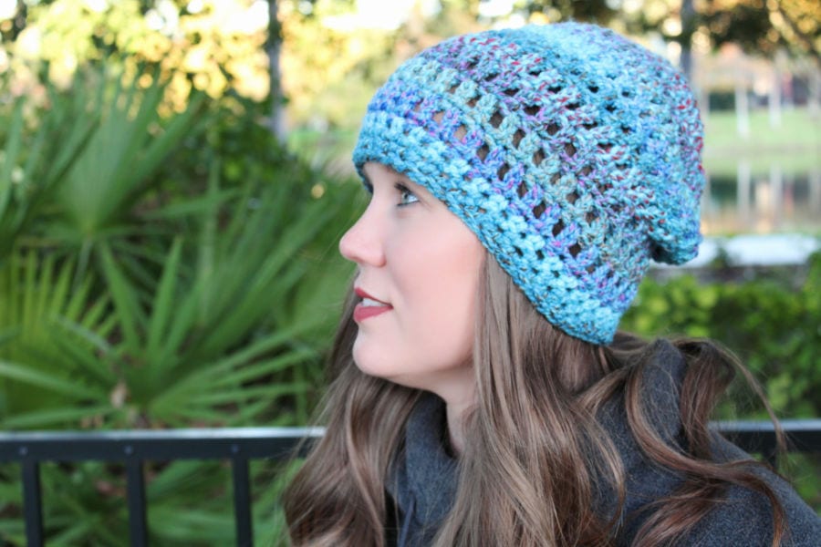 Woman wearing a blue crochet slouch hat, called the Easy Peasy Slouch. 