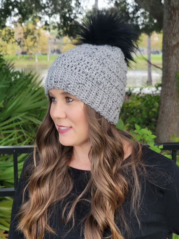 Woman wearing a gray tweed crochet hat, called the Edgewater Hat. 