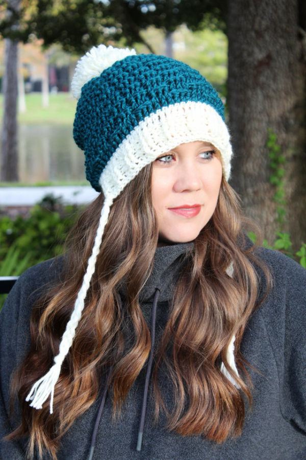 Woman wearing a green and cream colored crochet hat. 