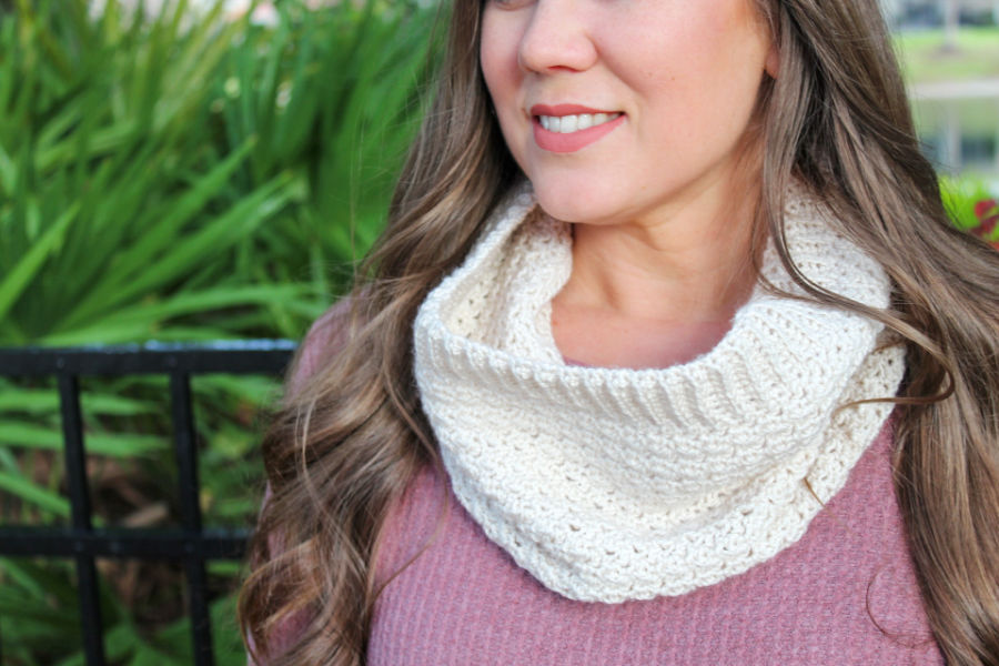 Close up image of woman wearing a cream colored crochet cowl, called the Camellia Cowl. 