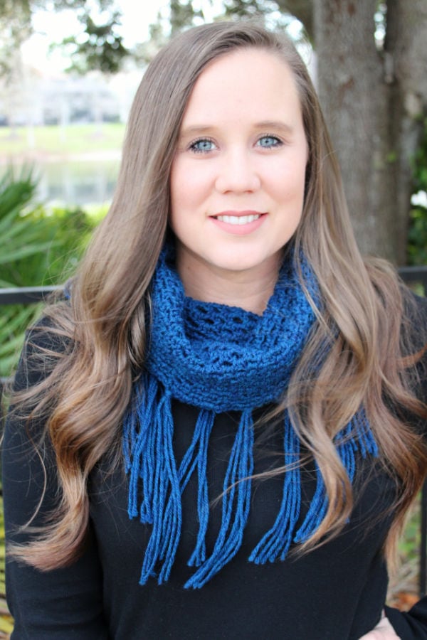 Woman wearing a blue crochet cowl with fringe, called the Georgia Cowl. 