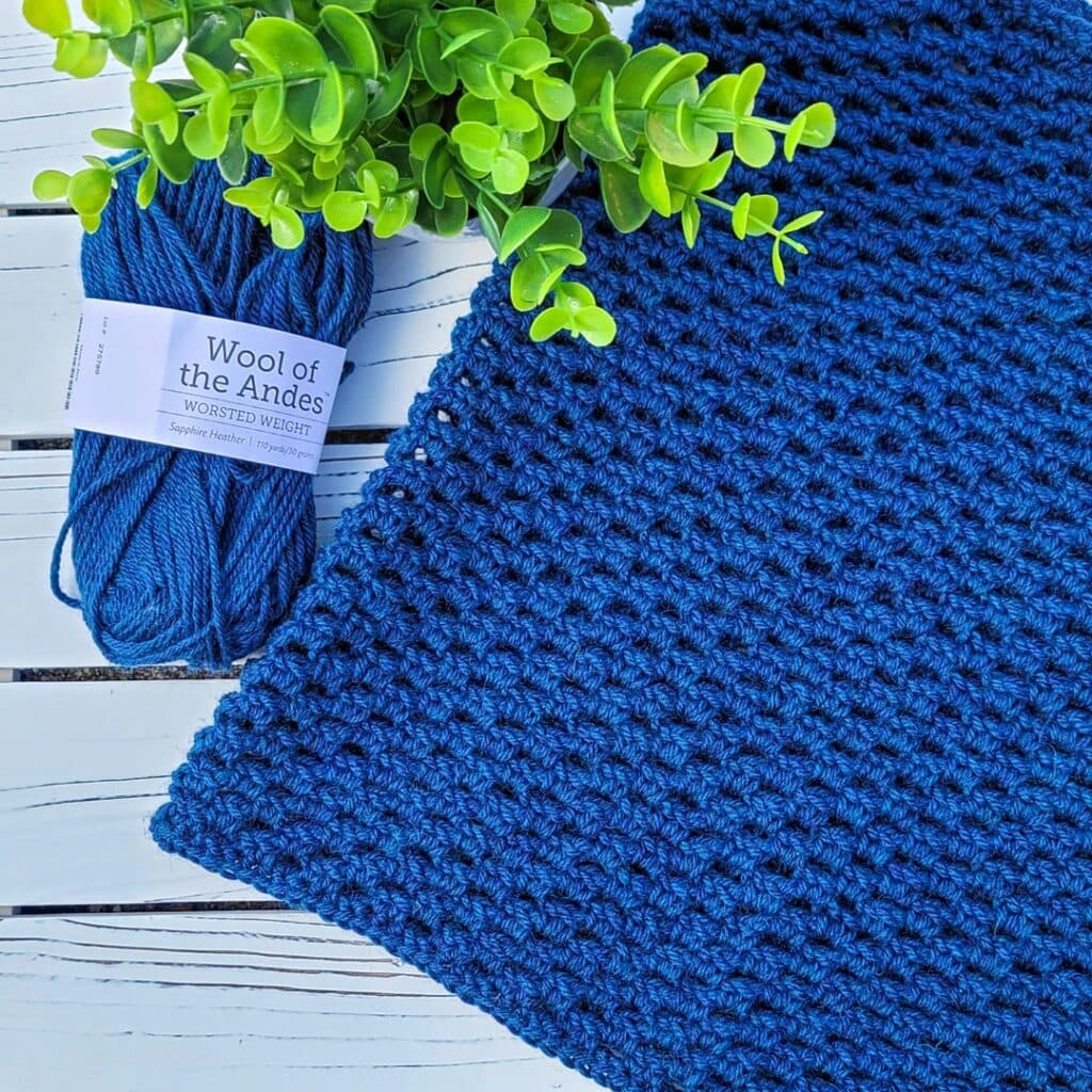 Flat lay photo of blue crochet cowl, called the Georgia Cowl.