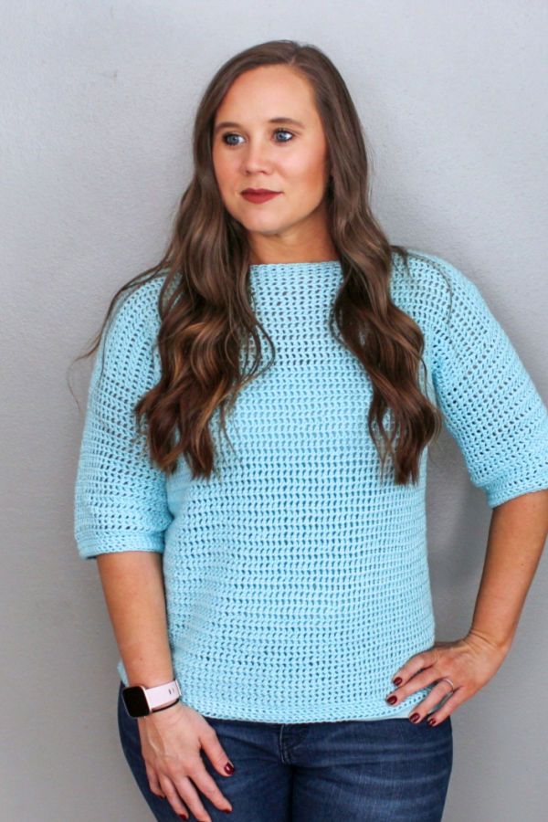 Woman wearing a light blue crochet sweater, called the Springtime Sweater. 