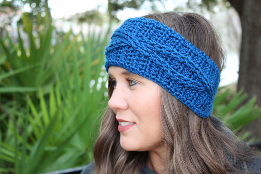 Close up of woman wearing a cabled crochet headband, called the Crossroads Headband. 