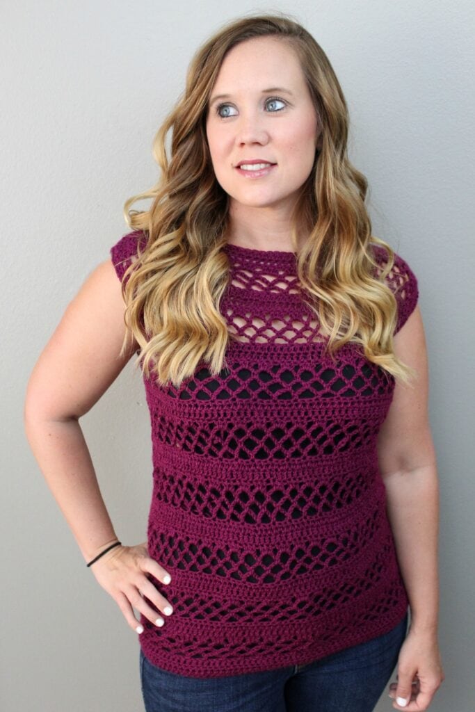 Woman wearing a purple crochet top. 