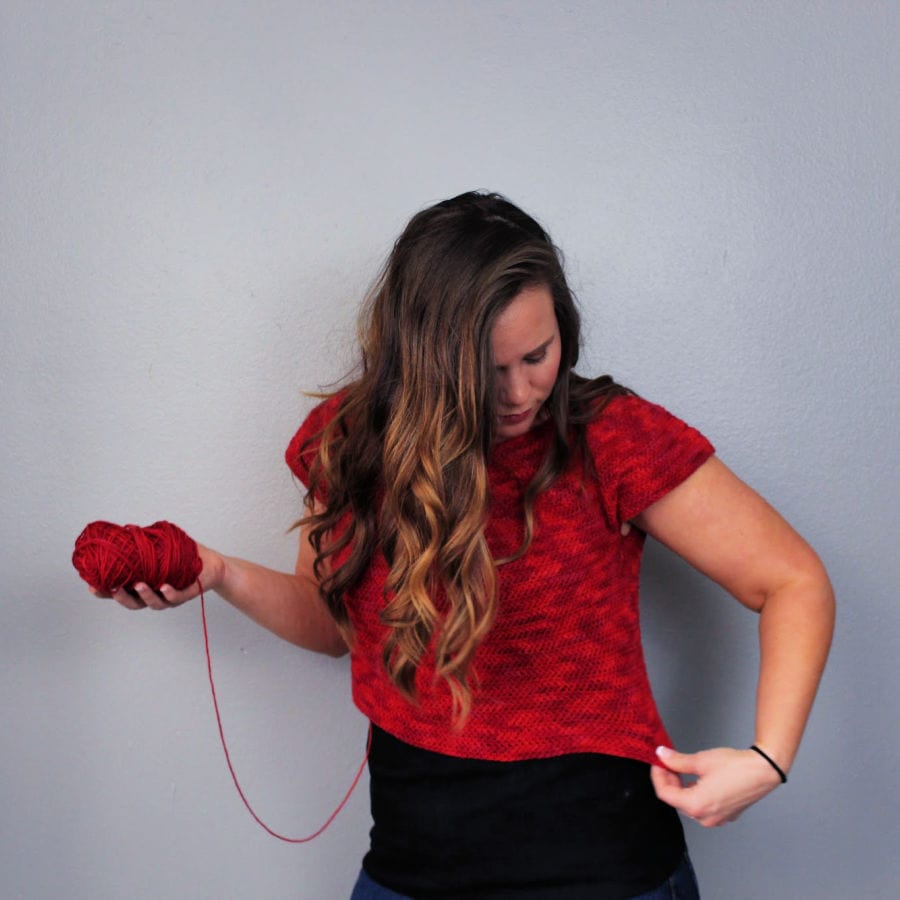 Woman trying on a crocheted top. 