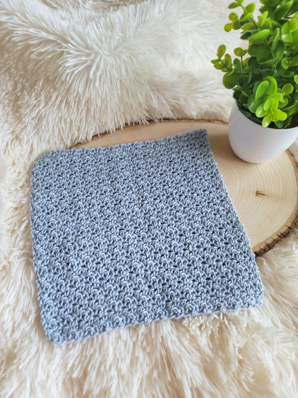 Light blue crochet washcloth pattern called the Camellia Washcloth. 