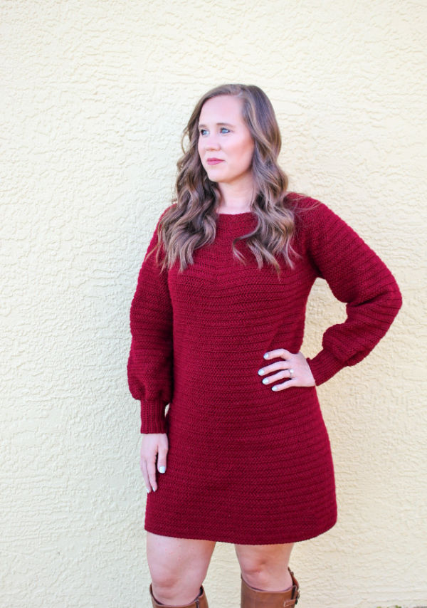 Woman wearing a maroon colored crochet sweater dress, called the Delaney Sweater Dress.