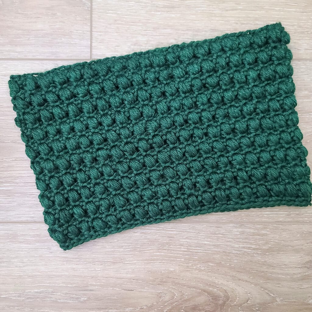 Flat lay image of a green crochet cowl, called the Winter Blooms Cowl.