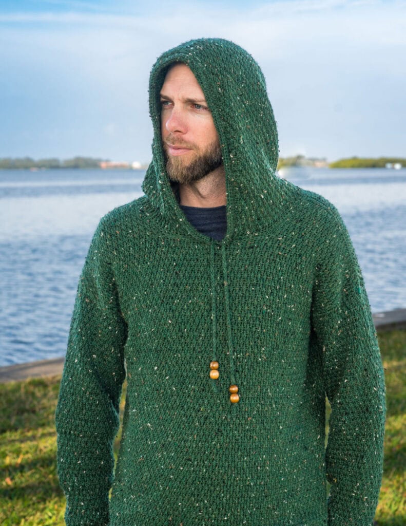 Close up of man wearing a green crochet hoodie, called the Dutton Hoodie.