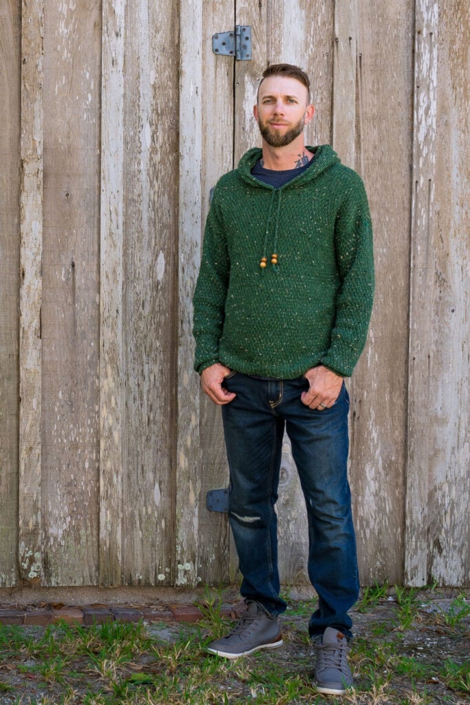 Man wearing a green crochet hoodie, called the Dutton Hoodie.