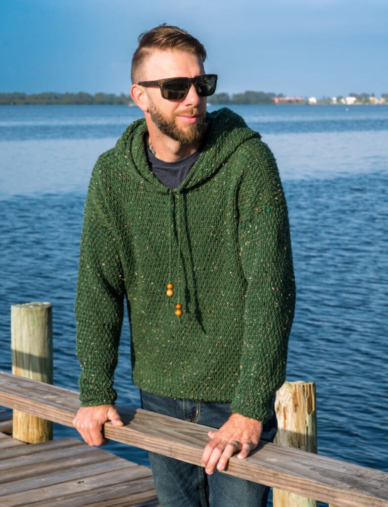 Man wearing a green crochet hoodie, called the Dutton Hoodie.