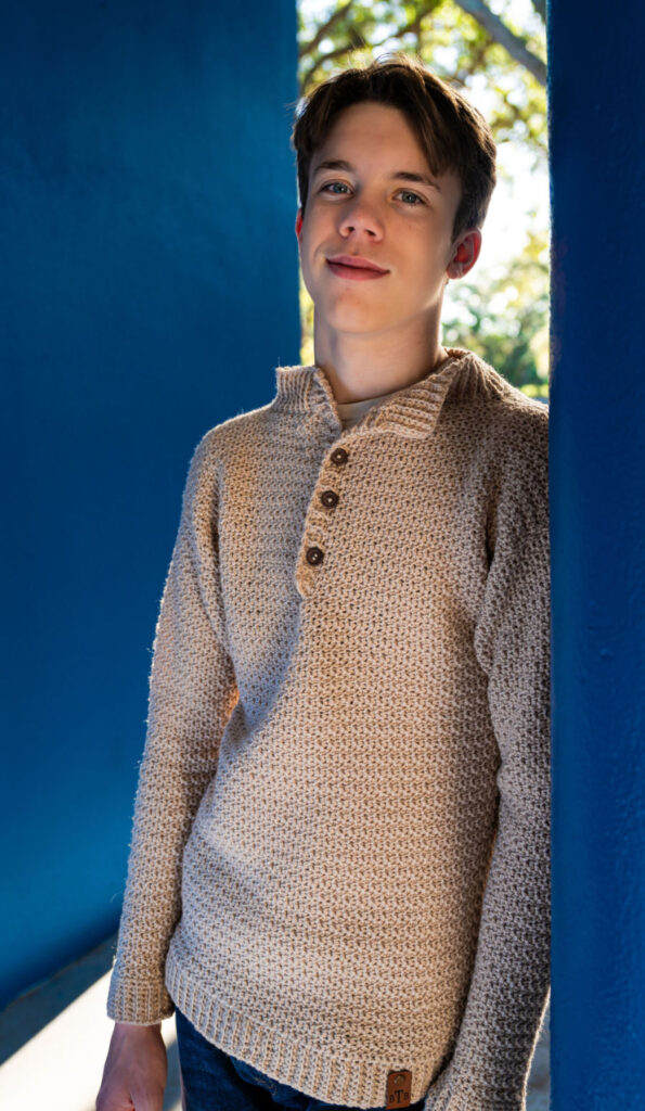 Young man wearing a men's crochet sweater, called the Bramley Sweater. 