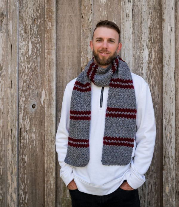 Man wearing a striped crochet scarf, called the Dooley Scarf.