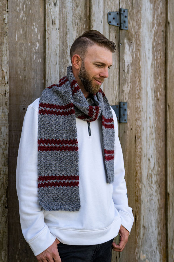 Man wearing a striped crochet scarf, called the Dooley Scarf.