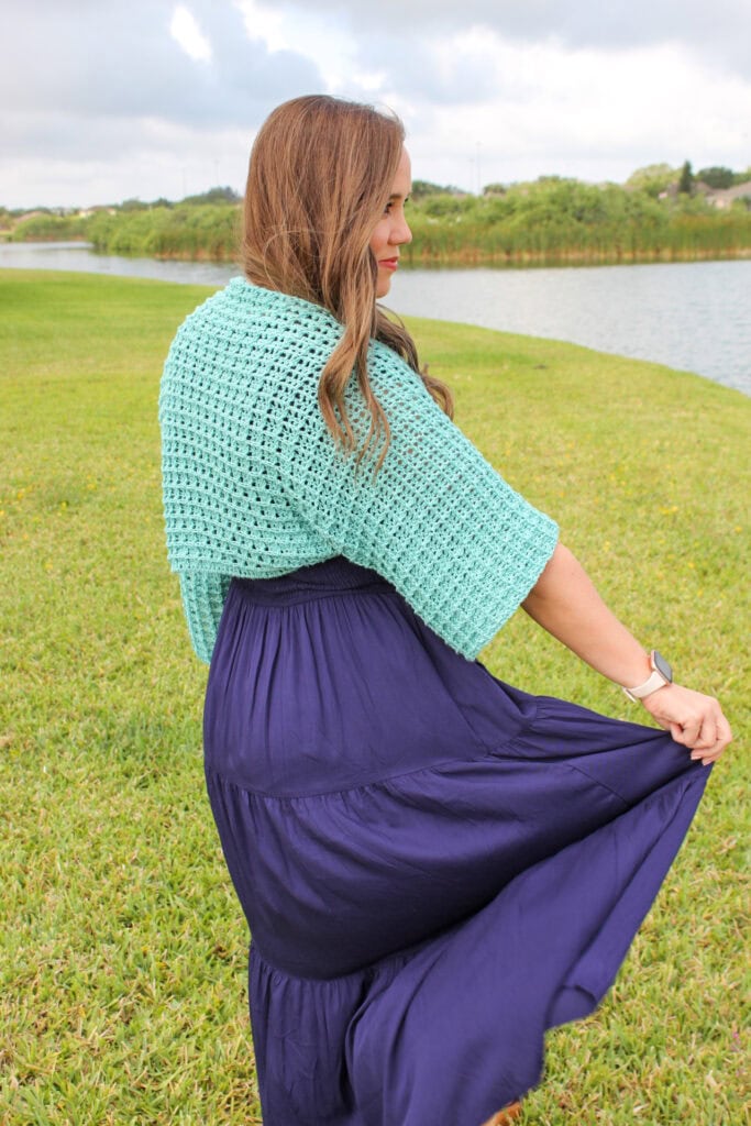 Woman wearing a light blue crochet shrug. 