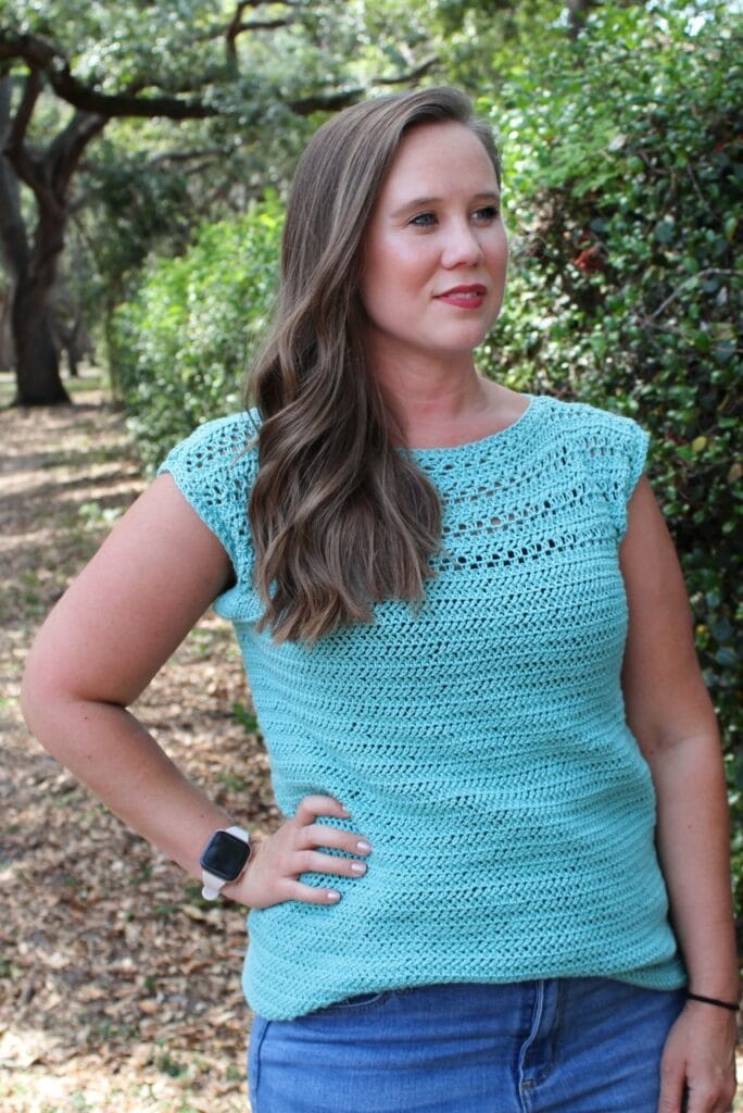 Woman wearing a summer crochet top, called the Marinna Tee. 