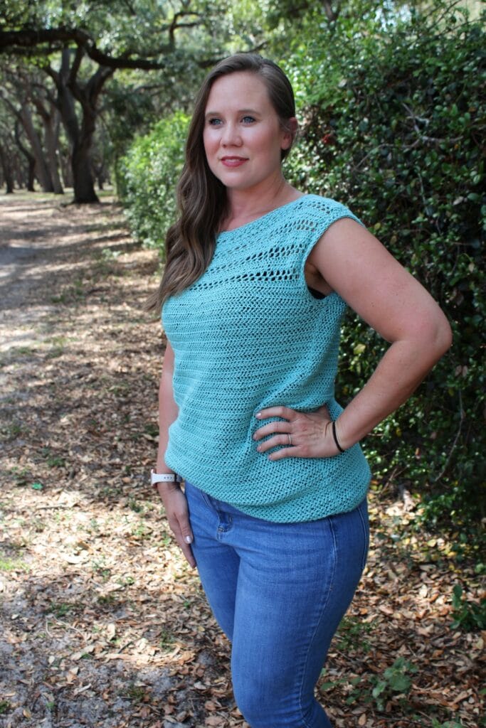 Woman wearing a summer crochet top, called the Marinna Tee. 