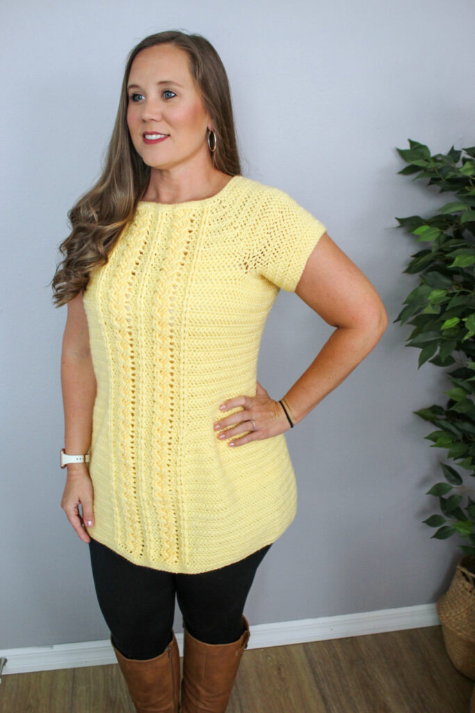 Woman wearing a yellow cabled crochet tunic, called the Aspen Tunic.